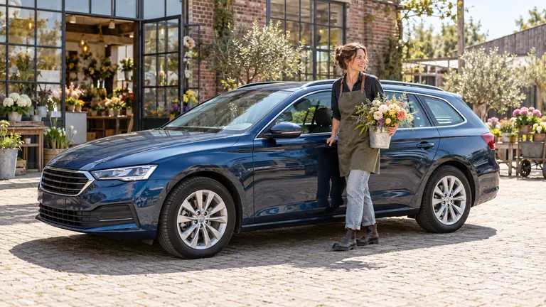 Een bloemiste met een bos bloemen naast haar blauwe stationwagen, voor haar atelier.